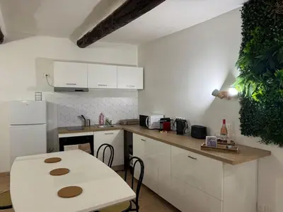 a white kitchen with a table and a white refrigerator at Appartement T2 Cosy centre-ville in Pernes-les-Fontaines