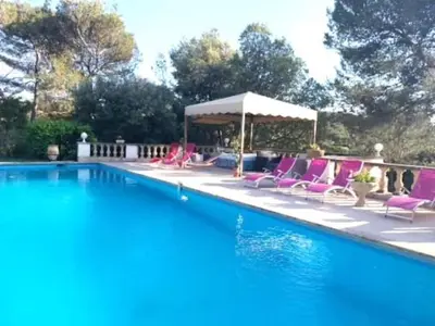 a swimming pool with pink chairs and a gazebo at La Louvière Plaine d'Eygalières in Orgon