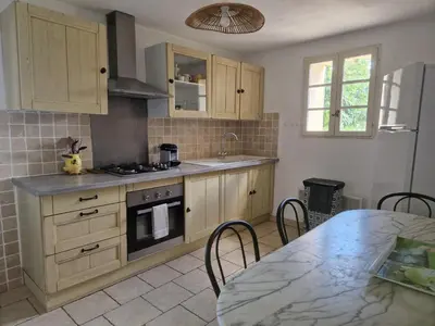 a kitchen with wooden cabinets and a table with a counter top at Villa Trempadou in Gordes