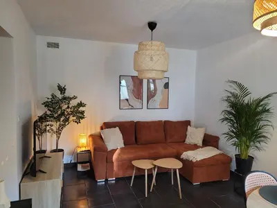 a living room with a brown couch and two tables at Appartement cosy avec exterieur au coeur de la Provence in Monteux