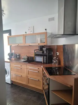 a kitchen with wooden cabinets and a stove top oven at Appartement cosy avec exterieur au coeur de la Provence in Monteux