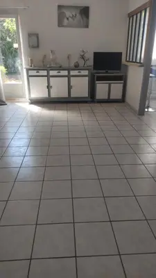 a living room with a tiled floor with a television at L'Appart in Cheval-Blanc