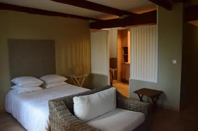 a bedroom with a white bed and a chair at La Chambre des Amis au Moulin des GYPSES, Ventoux in Mormoiron