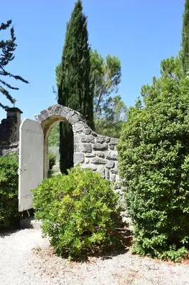 a stone archway in a garden with two bushes at La Chambre des Amis au Moulin des GYPSES, Ventoux in Mormoiron