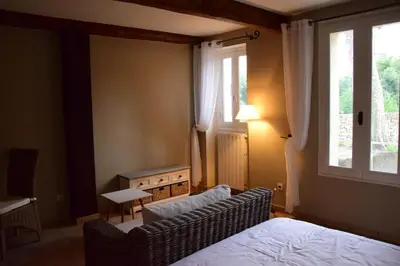 a bedroom with a bed and a couch and a window at La Chambre des Amis au Moulin des GYPSES, Ventoux in Mormoiron