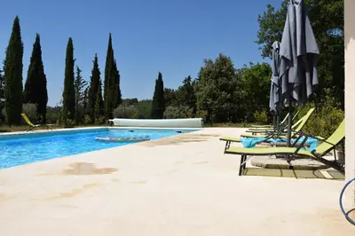 a swimming pool with lounge chairs and an umbrella at La Chambre des Amis au Moulin des GYPSES, Ventoux in Mormoiron