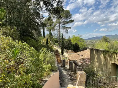 a path through a garden with trees and bushes at L'Irisciabella in Lourmarin