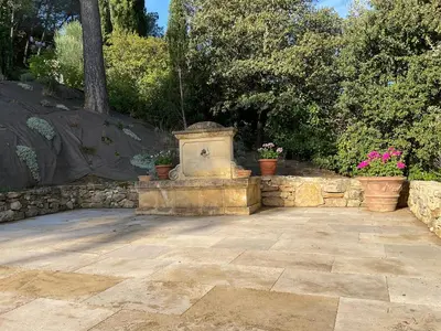 a stone fountain in a yard with potted plants at L'Irisciabella in Lourmarin