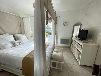 a white bedroom with a bed and a television at Le petit paradis au cœur du Luberon in Saint-Saturnin-les-Apt