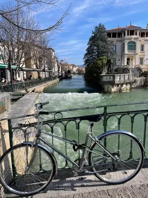 a bike parked next to a fence next to a river at A l'ombre des oliviers in LʼIsle-sur-la-Sorgue