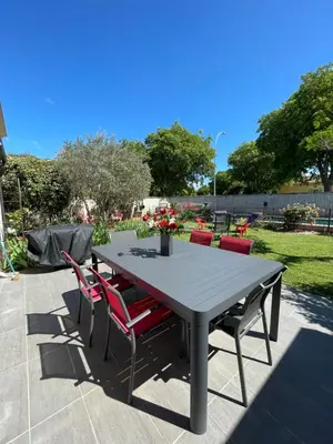 a picnic table with red chairs sitting around it at A l'ombre des oliviers in LʼIsle-sur-la-Sorgue