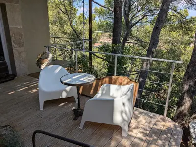 a porch with two chairs and a table on a deck at Charme, vue et piscine naturelle in Vedène