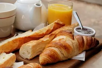 a table with a plate of bread and orange juice at Charme, vue et piscine naturelle in Vedène
