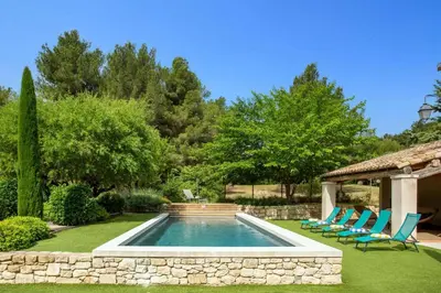 a swimming pool in a yard with chairs and a gazebo at Villa Les Alpilles by Villa Plus in Mouriès