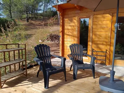 two chairs sitting on a porch of a cabin at Escapade sous les pins 20m2 in Aurons