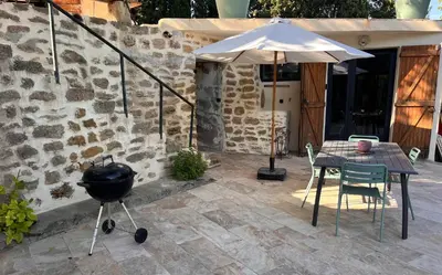 a grill and a table with a grill and an umbrella at Évasion charme et jacuzzi en pleine nature in Grans
