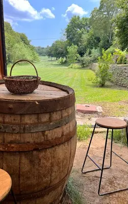 a wooden barrel with a basket and two stools at Évasion charme et jacuzzi en pleine nature in Grans