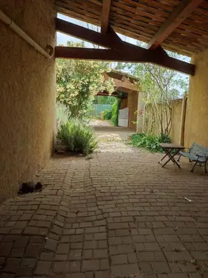 an empty patio with a bench and a wooden roof at Maison provençale au milieu des champs in Robion en Luberon