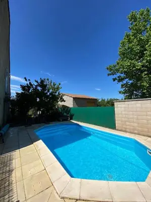 a large blue swimming pool next to a building at Maison provençale au milieu des champs in Robion en Luberon