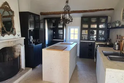 a large kitchen with blue cabinets and a fireplace at Village home in Ménerbes in Ménerbes