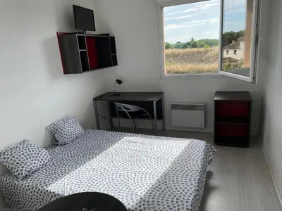 a bedroom with a bed and a desk and a window at Joli appartement sur Aix-en-Provence in Aix-en-Provence