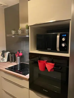 a kitchen with a microwave and a stove with red cups at Chaleureuse maison in Cavaillon