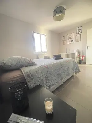 a bedroom with a bed with a candle on a table at Chaleureuse maison in Cavaillon