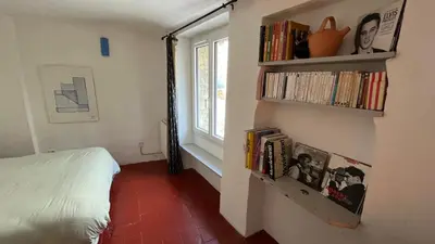a bedroom with a bed and shelves with books at Charmante petite maison à Murs in Murs