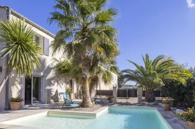 a swimming pool with palm trees in front of a house at Source de Vie in Noves