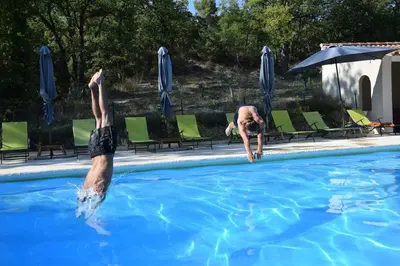 two men are diving into a swimming pool at Moulin des Gypses Gîte Les Pampres, Ventoux in Mormoiron