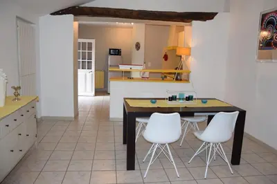 a kitchen with a table and two white chairs at Moulin des Gypses Gîte l'Oliveraie, Ventoux in Mormoiron