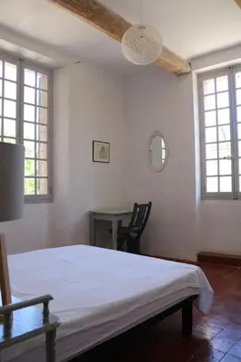 a bedroom with a bed and a table and windows at Mas Provencal Monteux 84170 in Althen-des-Paluds