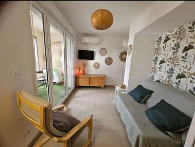 a living room with a couch and a chair and a television at Au petit coeur de l'isle in LʼIsle-sur-la-Sorgue