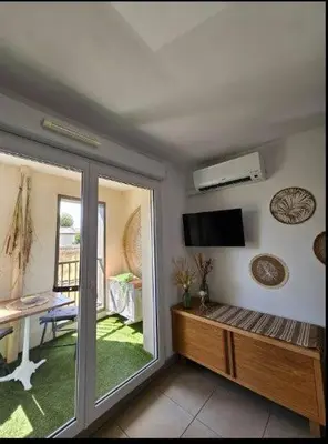 a living room with a sliding glass door with a television at Au petit coeur de l'isle in LʼIsle-sur-la-Sorgue