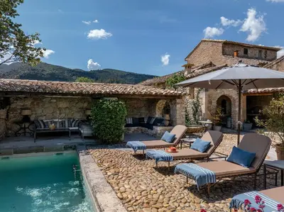 a house with a swimming pool with chairs and an umbrella at Villa Syrah, La Bastide de Marie, Villa avec services in Ménerbes