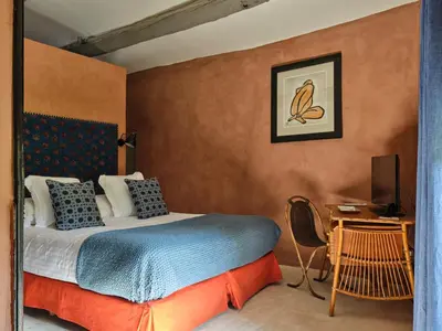 a bedroom with a bed and a desk with a television at Villa Syrah, La Bastide de Marie, Villa avec services in Ménerbes