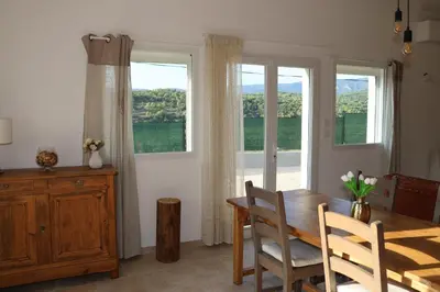a dining room with a table and chairs and windows at Les Vignes du Luberon in Saignon