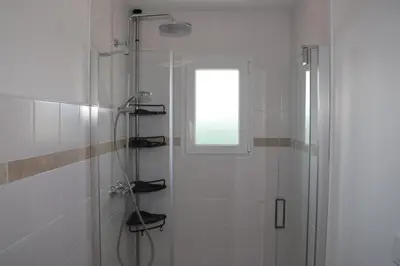 a white bathroom with a shower and a window at Les Vignes du Luberon in Saignon