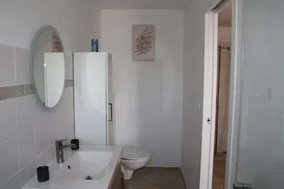 a white bathroom with a toilet and a sink at Les Vignes du Luberon in Saignon