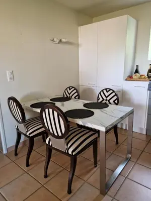 a dining room table with four chairs and a kitchen at Le Bastidon des Mésanges in Gordes