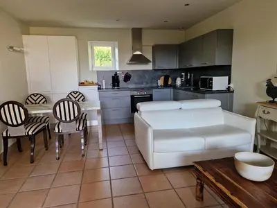 a living room with a white couch and a kitchen at Le Bastidon des Mésanges in Gordes