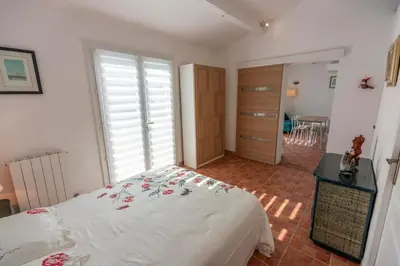 a bedroom with a white bed with flowers on it at Joli Studio 36m2 tout confort in Châteauneuf-de-Gadagne