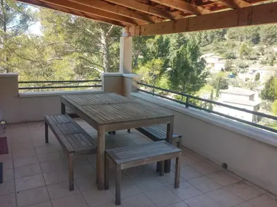 a wooden table and bench on a balcony at B&B Villa Chante Coucou in Fontaine-de-Vaucluse