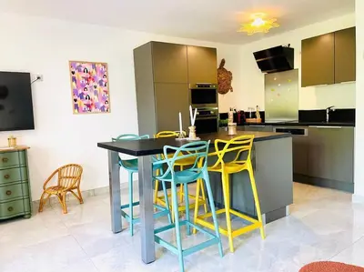 a kitchen with yellow and blue stools around a table at Maison haut de gamme dans le golf de pont royal in Mallemort