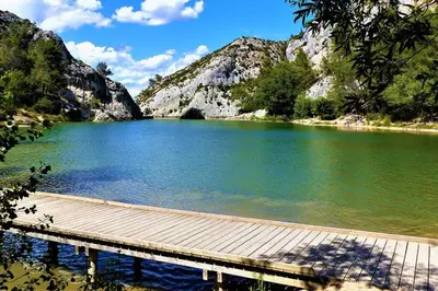 a dock on a lake with mountains in the background at Mazet Rigodon Alpilles in Eygalières