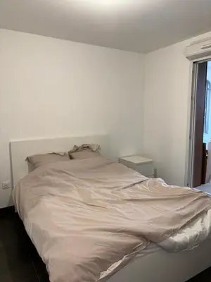a white bed in a white room with a window at Appartement T2 climatisé garage in Aix-en-Provence