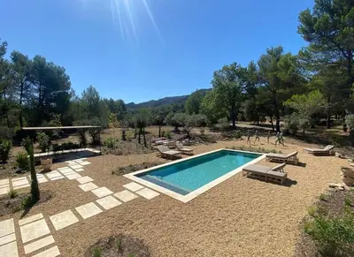 a swimming pool in a yard with chairs and a table at Bastide Farandole in Eygalières