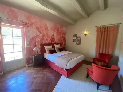 a bedroom with a bed and a red chair at Bastide Farandole in Eygalières