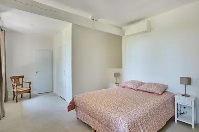 a white bedroom with a bed and a chair at Le Bastidon, Aix en Pce proche centre, climatisé, 4 chambres in Aix-en-Provence