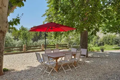 a wooden table and chairs with a red umbrella at Le Bastidon, Aix en Pce proche centre, climatisé, 4 chambres in Aix-en-Provence